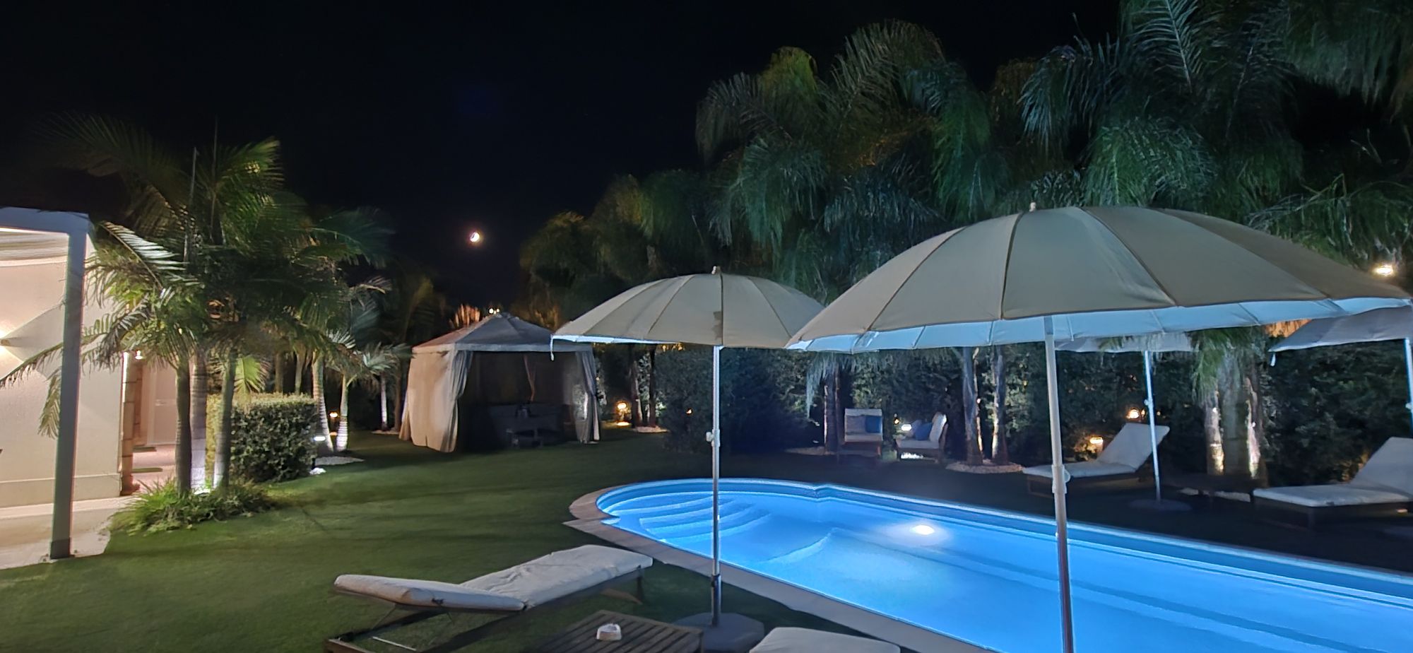 Piscina, ombrelloni e gazebo illuminati di sera
