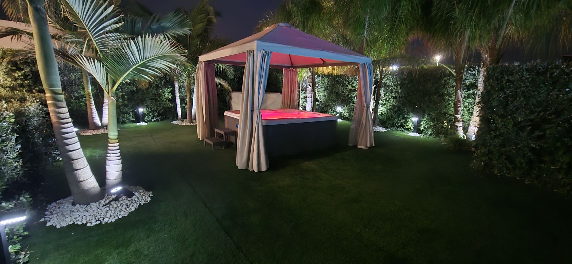 Il gazebo della jacuzzi illuminato di sera tra le palme