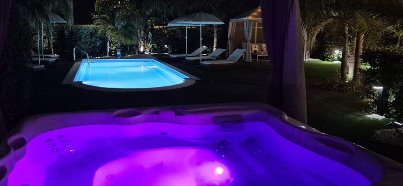 Jacuzzi illuminata di viola con la piscina sullo sfondo