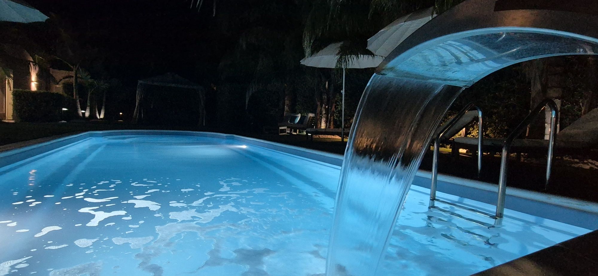 Piscina illuminata di sera con la cascata