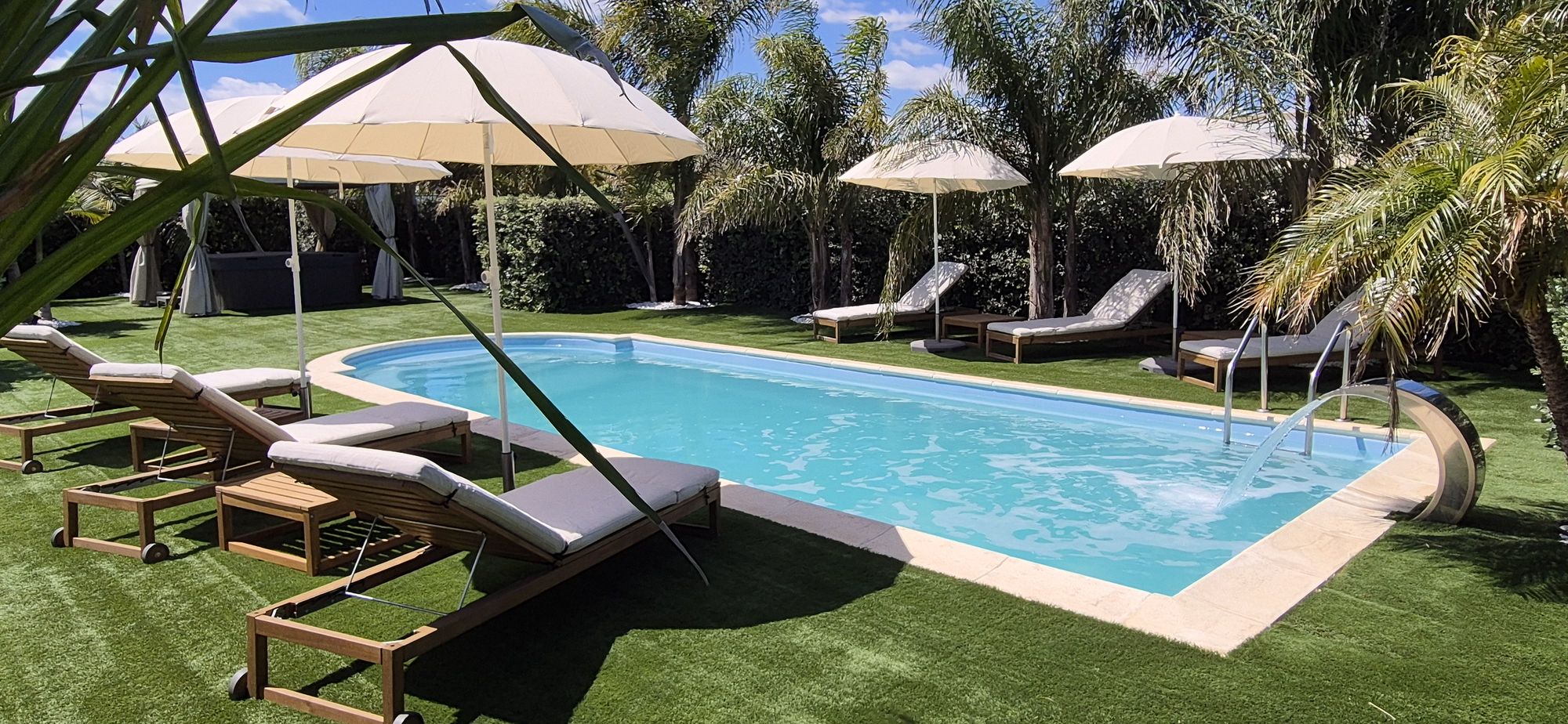 La piscina di acqua salata con lettini e ombrelloni tra le palme