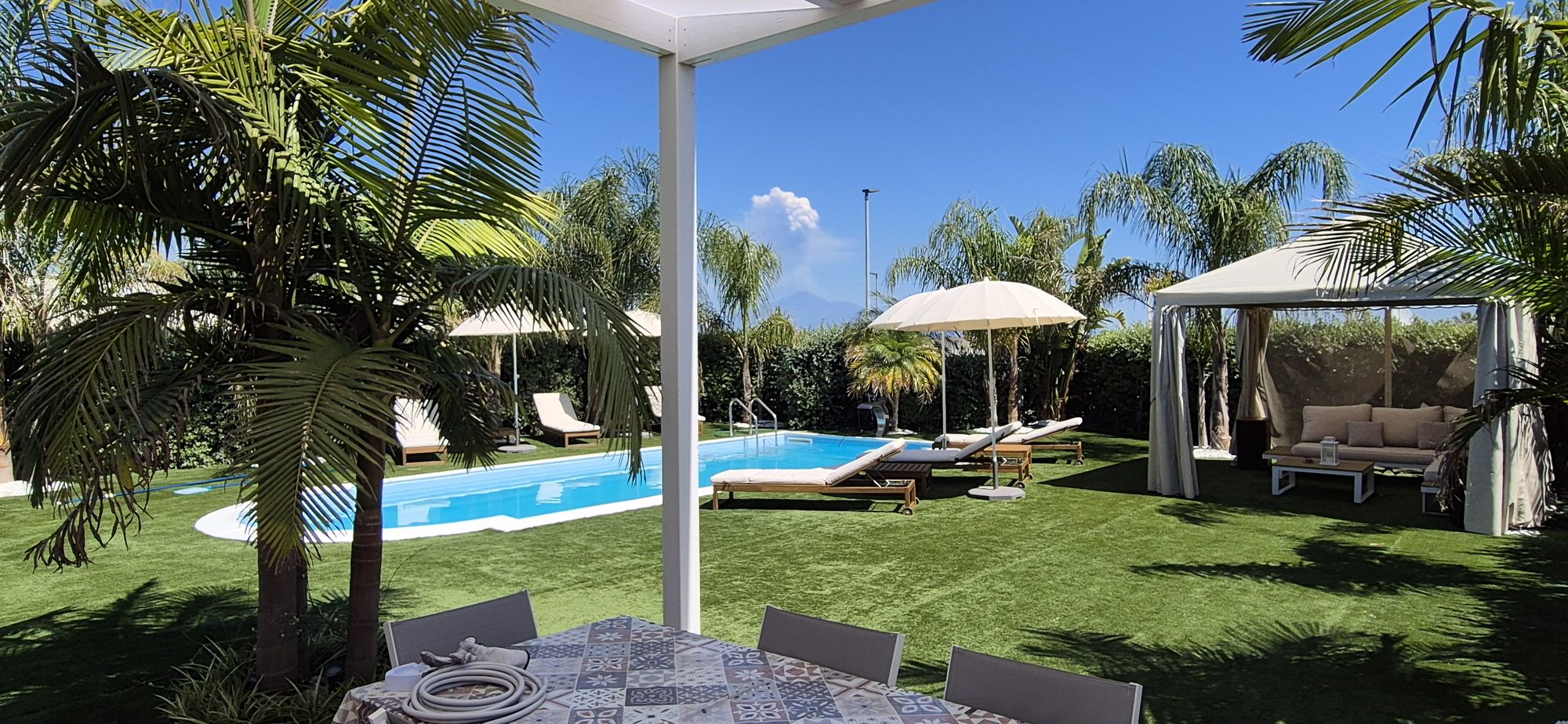 La veranda della villa con il tavolo da pranzo tra le palme