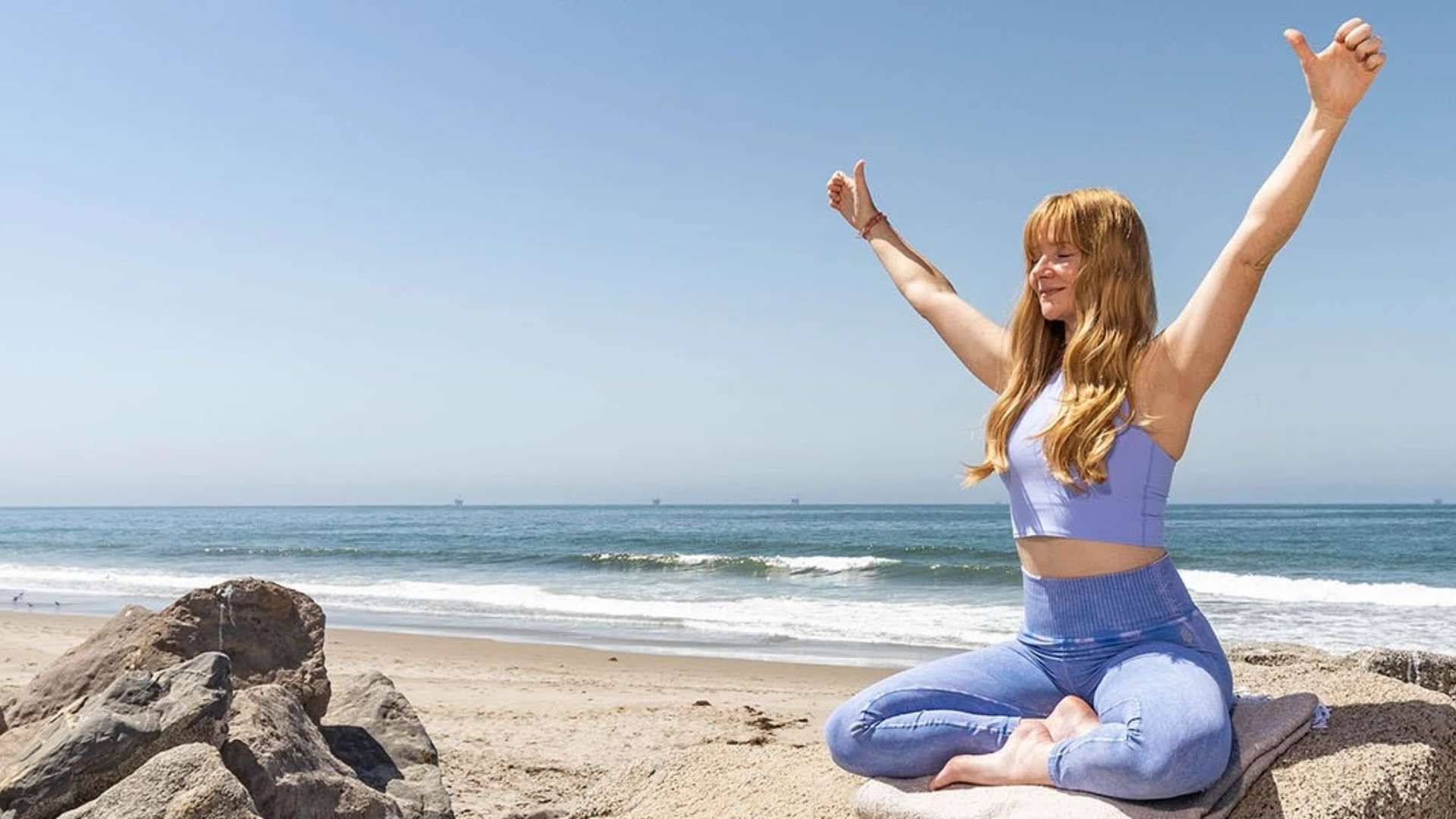 Ragazza che fa yoga sulla spiaggia davanti al mare